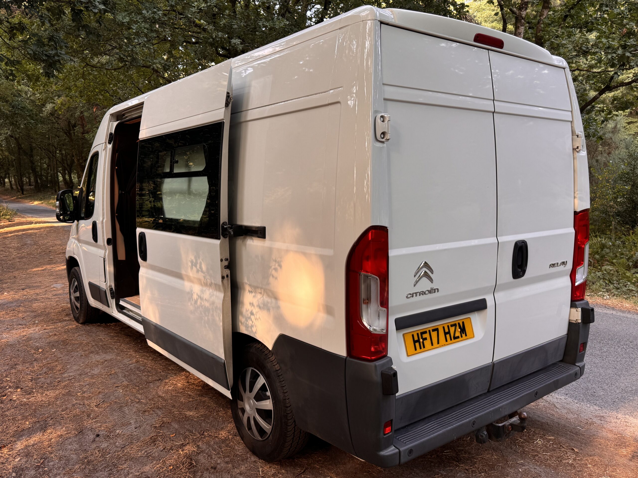White campervan rear three-quarter view in a wooded setting